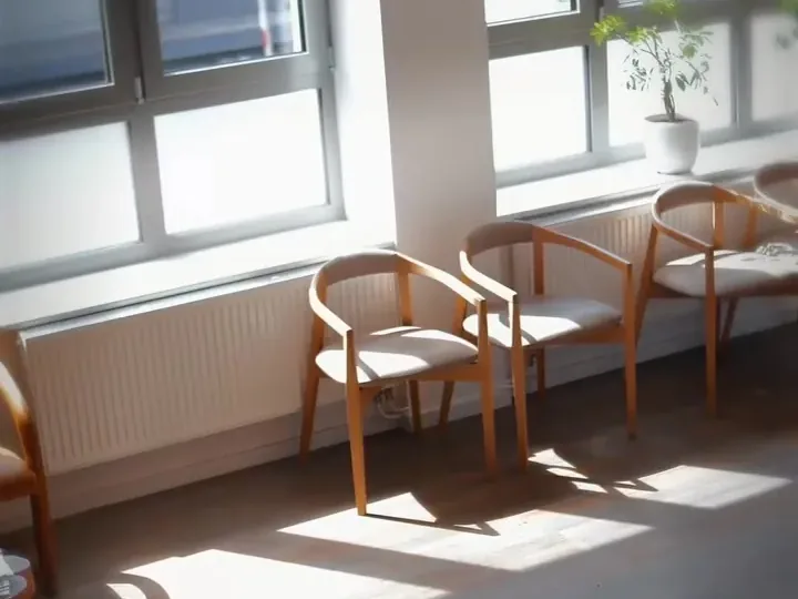 Wartebereich mit Holzstühlen und großen Fenstern bei der Corpus Callosum GmbH